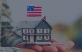 Military Member Holding Model House With US Flag