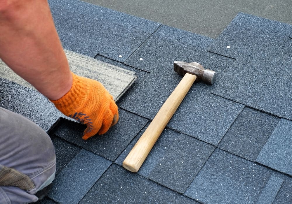 Close up of hands with orange work gloves laying down panels to repair roof